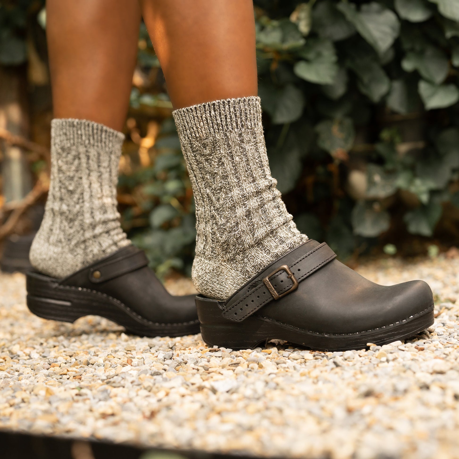 Black mule clogs with an adjustable strap styled with grey wool socks.