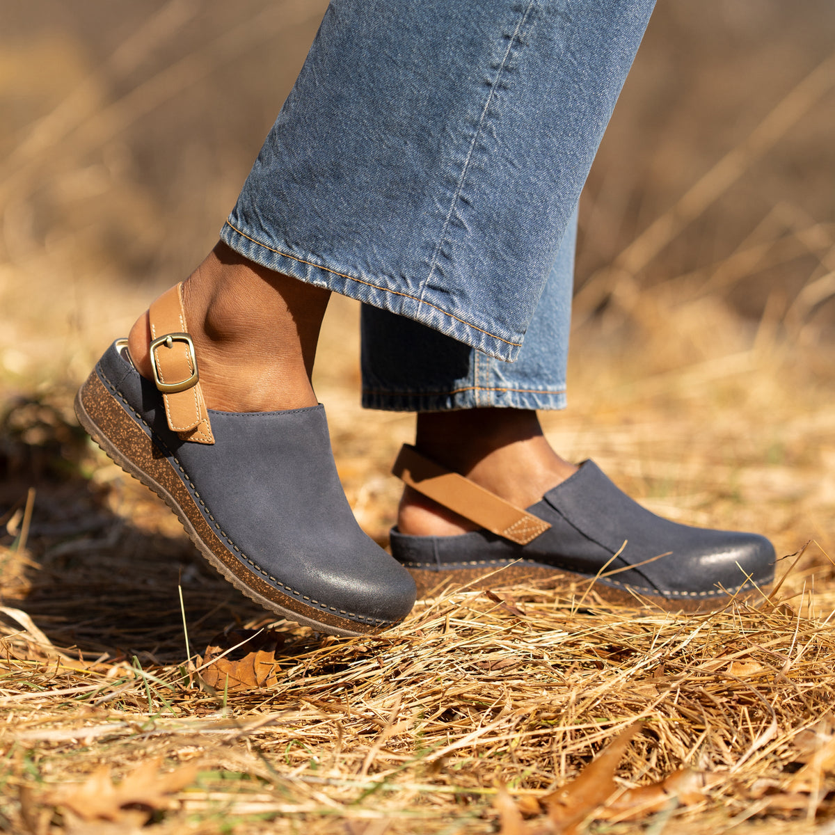 Blue leather clogs with cork soles and a brown leather heel strap shown on foot.